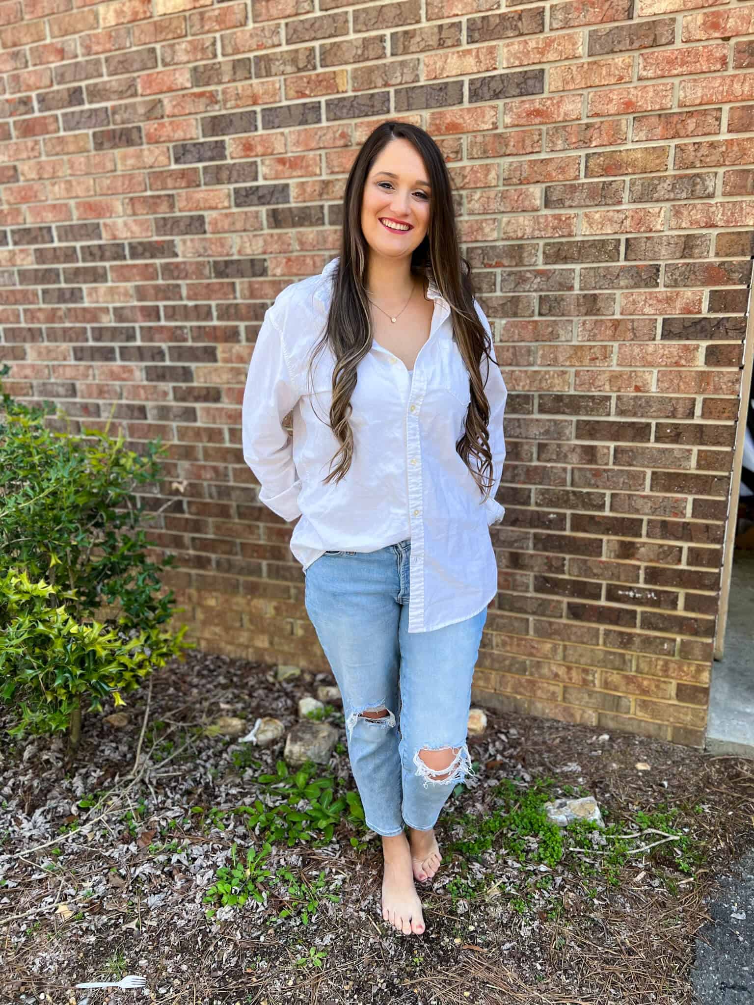 Bookkeeper Courtney Waters smiling and standing in front of a brick wall