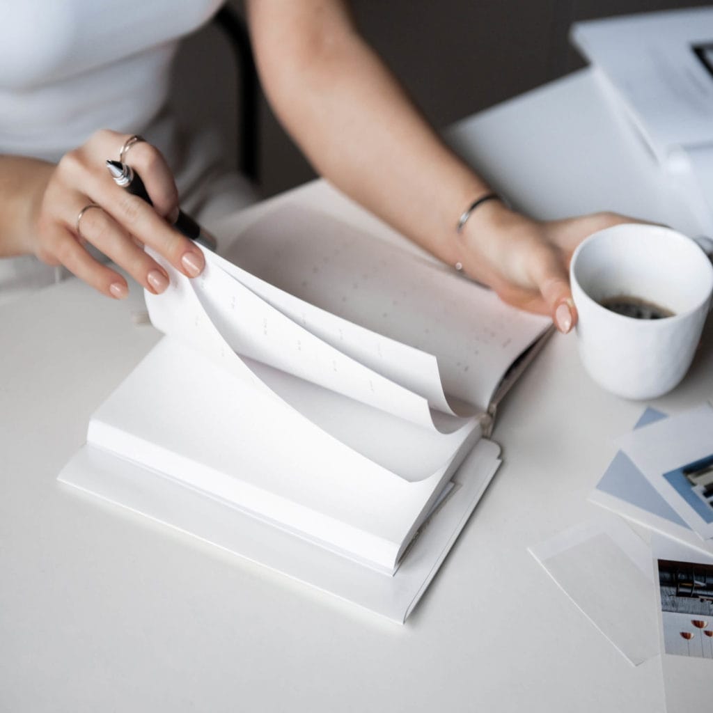 Woman working on small business bookkeeping with a journal and coffee