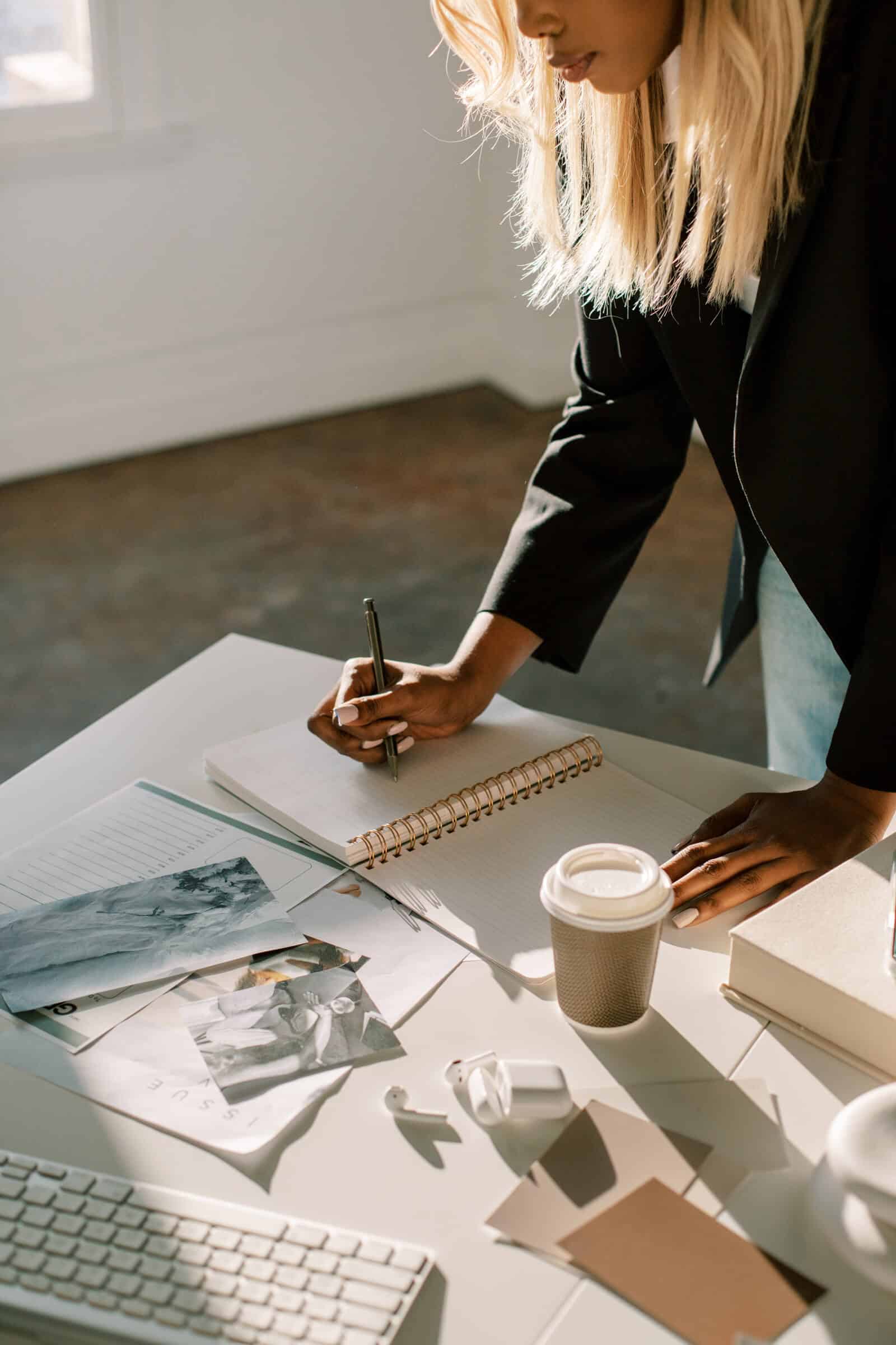 Woman standing at a desk writing in a notebook